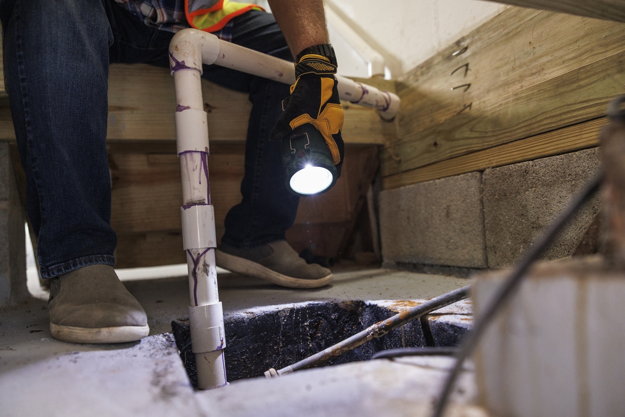Sump pit crash inspection. Unrecognizable insurance claim agent's hands with flashlight inspect Sump Pit pipes, looking for damage